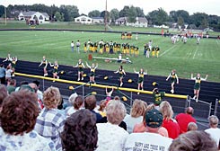 Townsfolk, along with a few cyclists, crowd a McBain High School junior varsity football game.