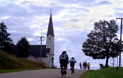 Cyclists climb a hill
            leading to a small Lutheran church on the road to West
            Bend.